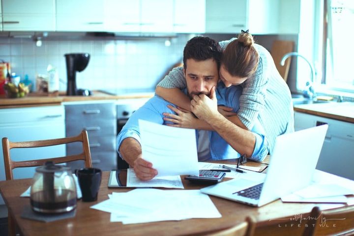 young couple going over expensive bills at kitchen table
