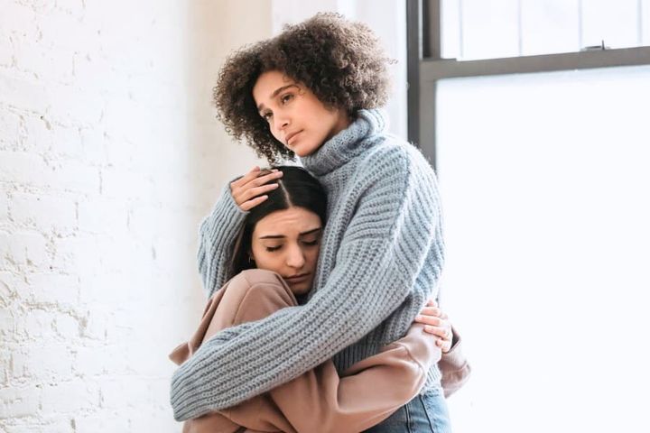 worried woman comforting her sad friend with a hug