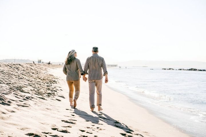 senior couple holding hands walking on beach