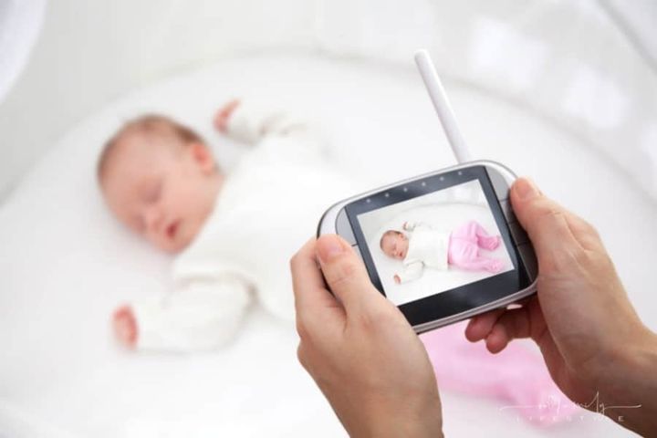 baby sleeping in background with baby monitor in foreground