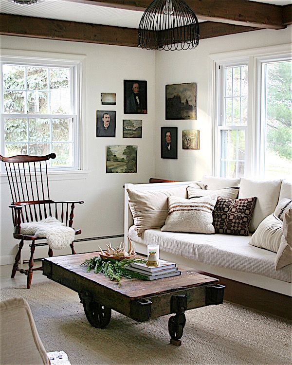 Modern country living room with industrial cart coffee table and landscapes and portraits on gallery wall.