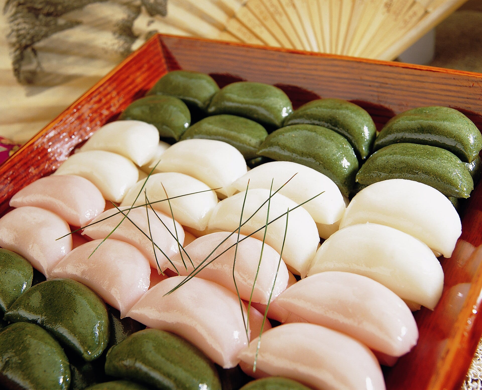 Tray of pink, white and green songpyeon with pine needles