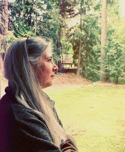 Roxanne Lynch in profile outdoors among tall trees, reflecting on Facebook search optimization and how social media visibility can support make money from home goals.