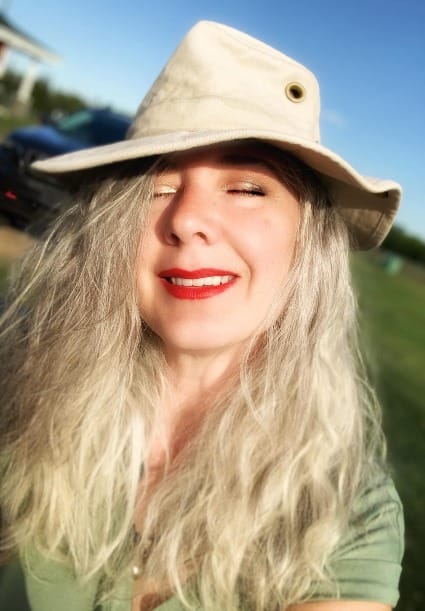 Roxanne Lynch smiling outdoors in the sunshine wearing a wide-brim hat, representing freedom, personal branding, and building make money from home visibility through Facebook SEO.