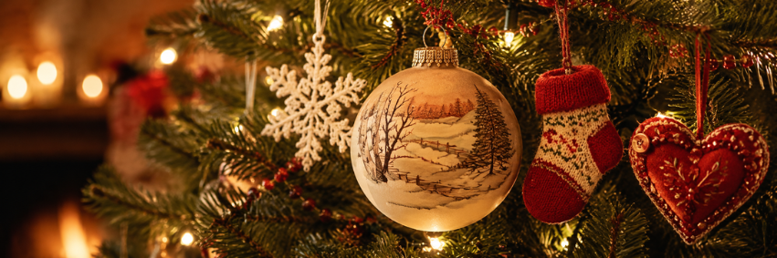 Handmade Christmas ornaments hanging on a warmly lit holiday tree.