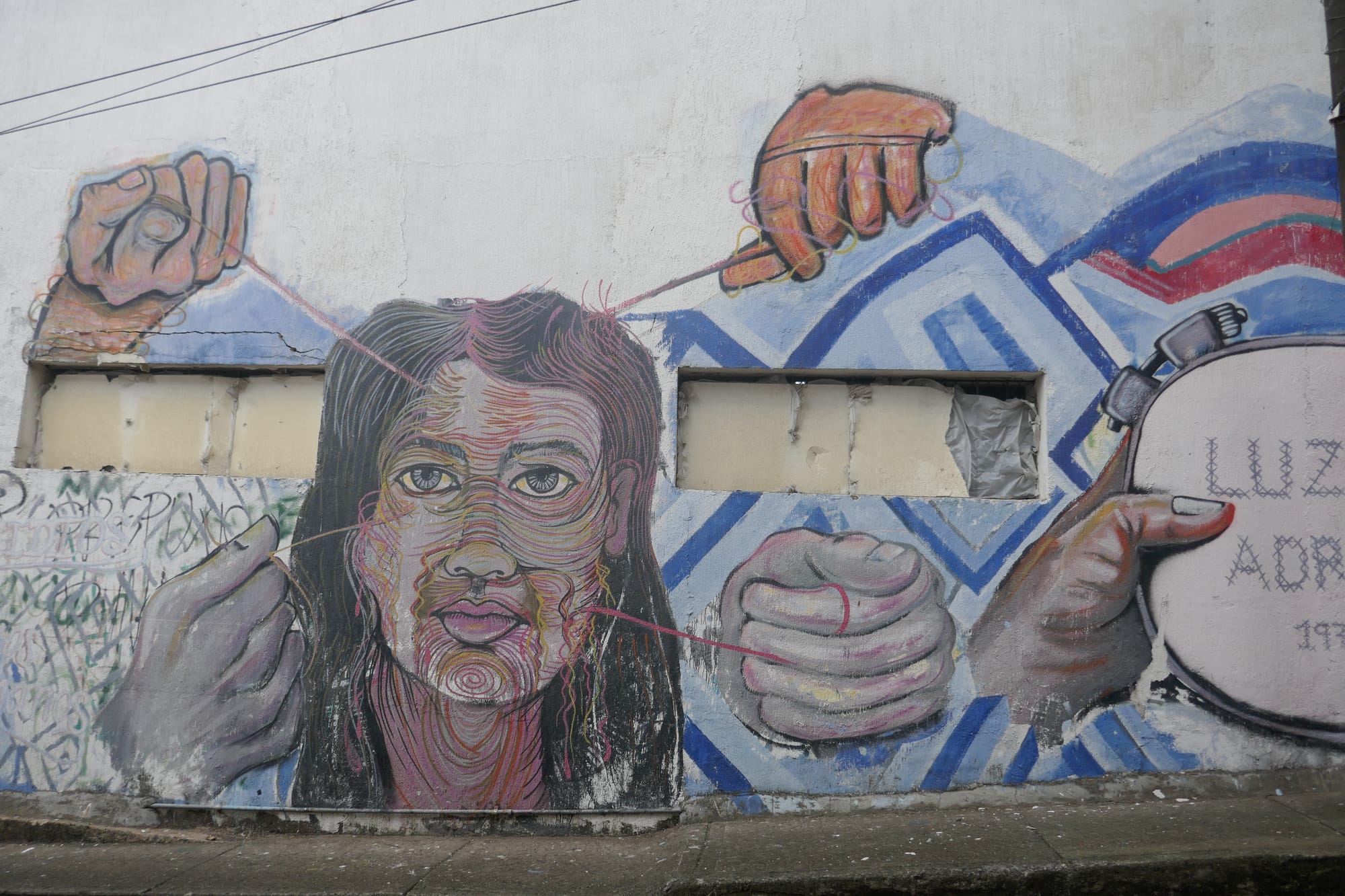 Graffiti sur un mur de Cali de plusieurs mains détricotant le visage d'une femme