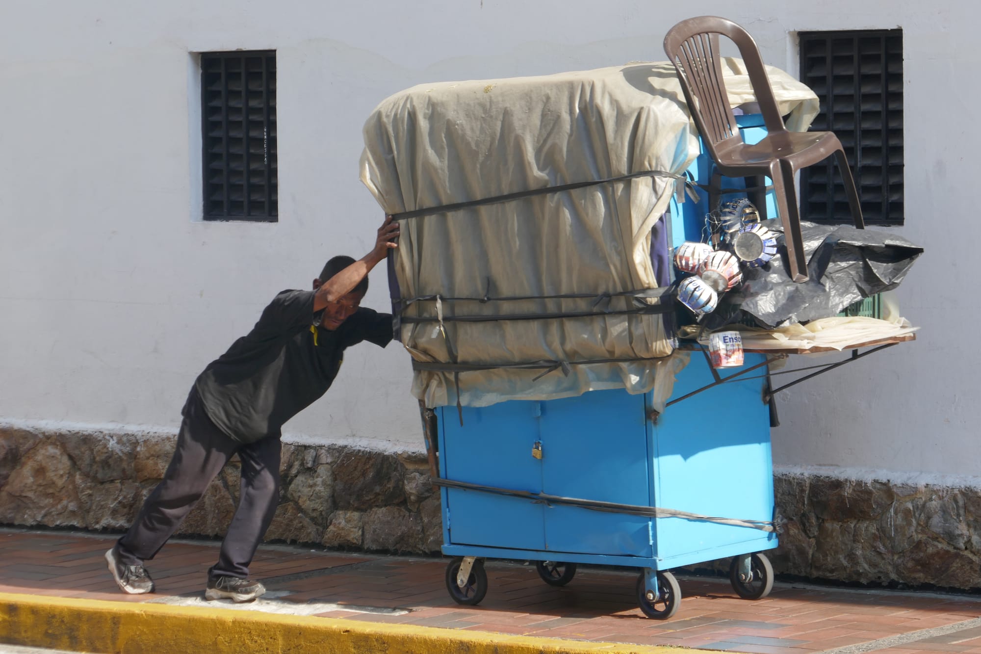 Homme à Cali poussant un chariot plein d'affaires.