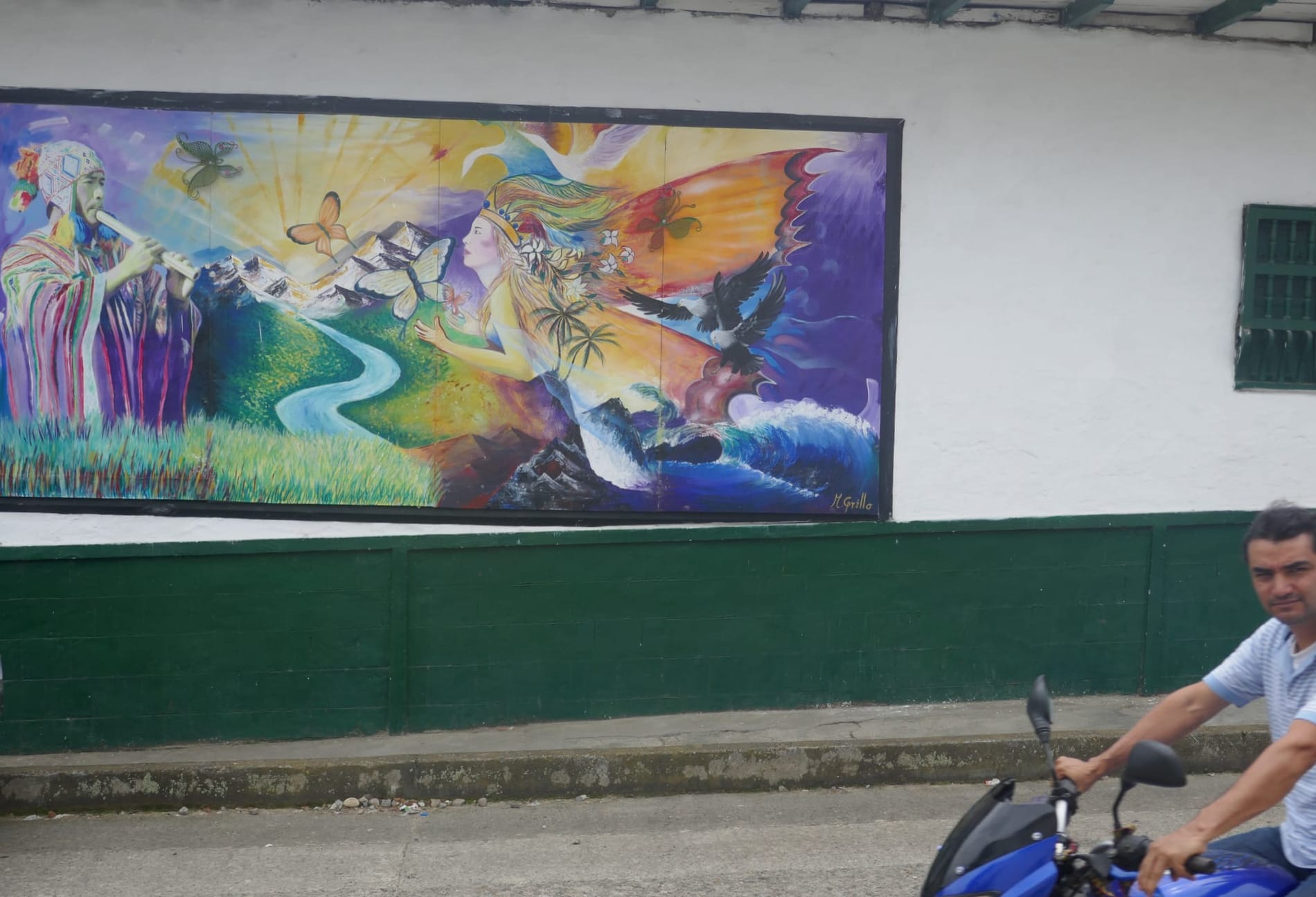 Photo d'une peinture murale représentant un homme en tenue traditionnelle jouant de la flûte et une femme volant au dessus d'une vague, dans la ville de San Agustín.