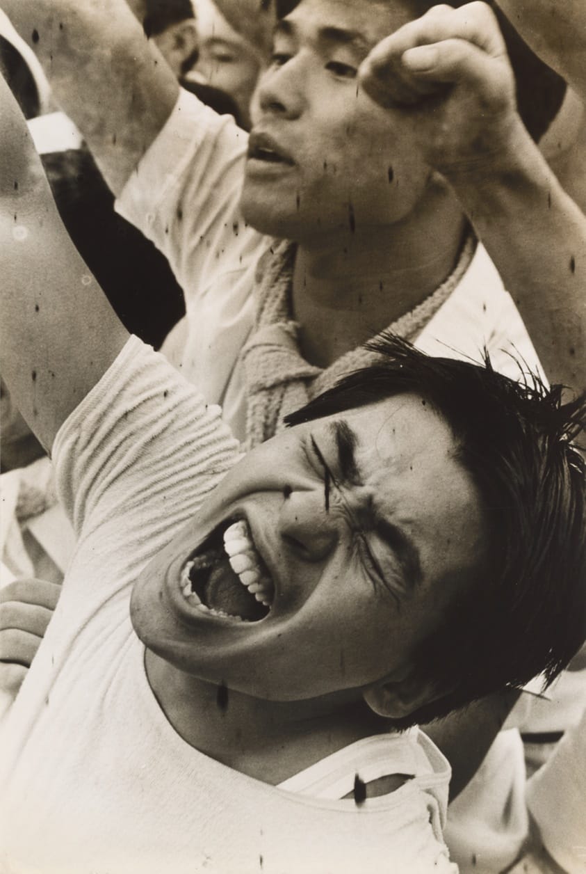 Photo d'une foule d'hommes japonais levant le point en signe de protestation.