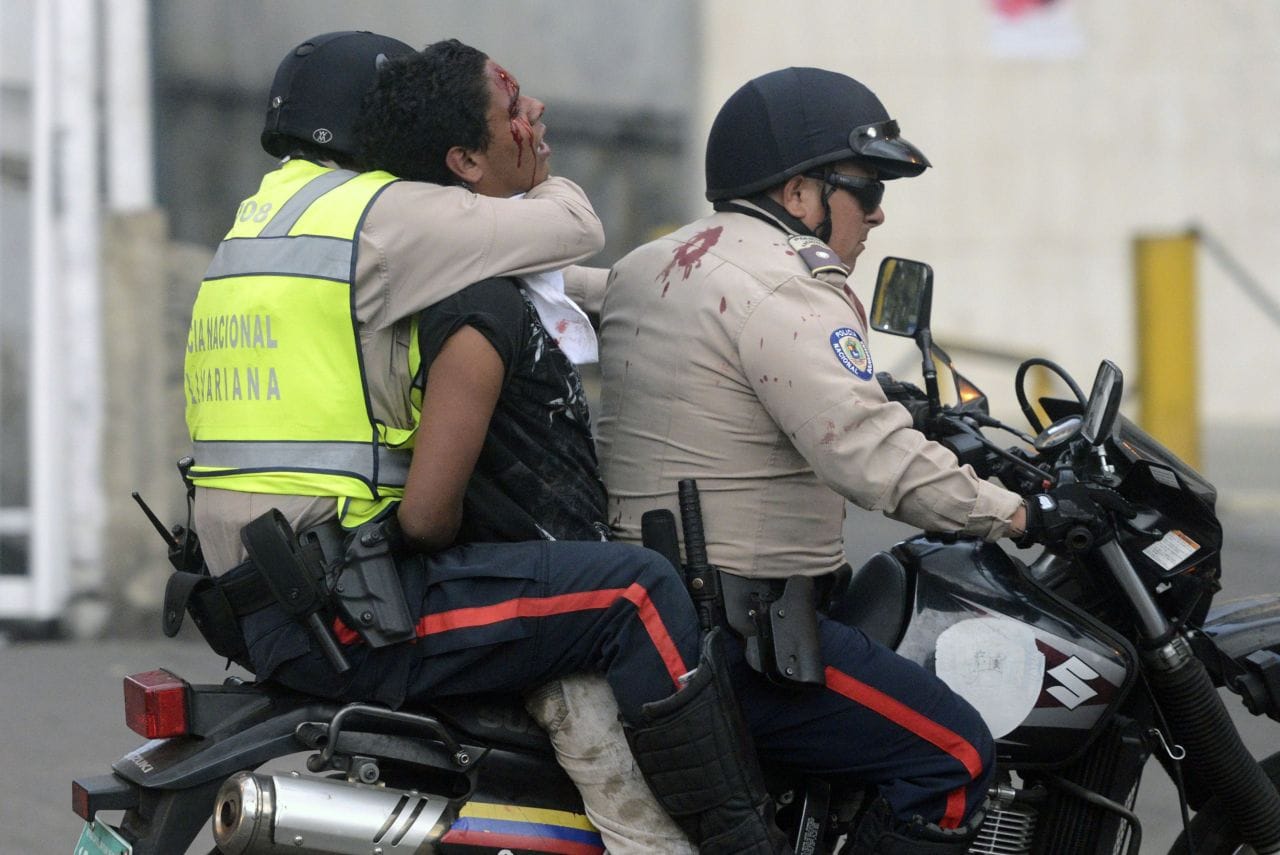 Un manifestant au Venezuela est enlevé par deux agents de la garde nationale sur une moto.