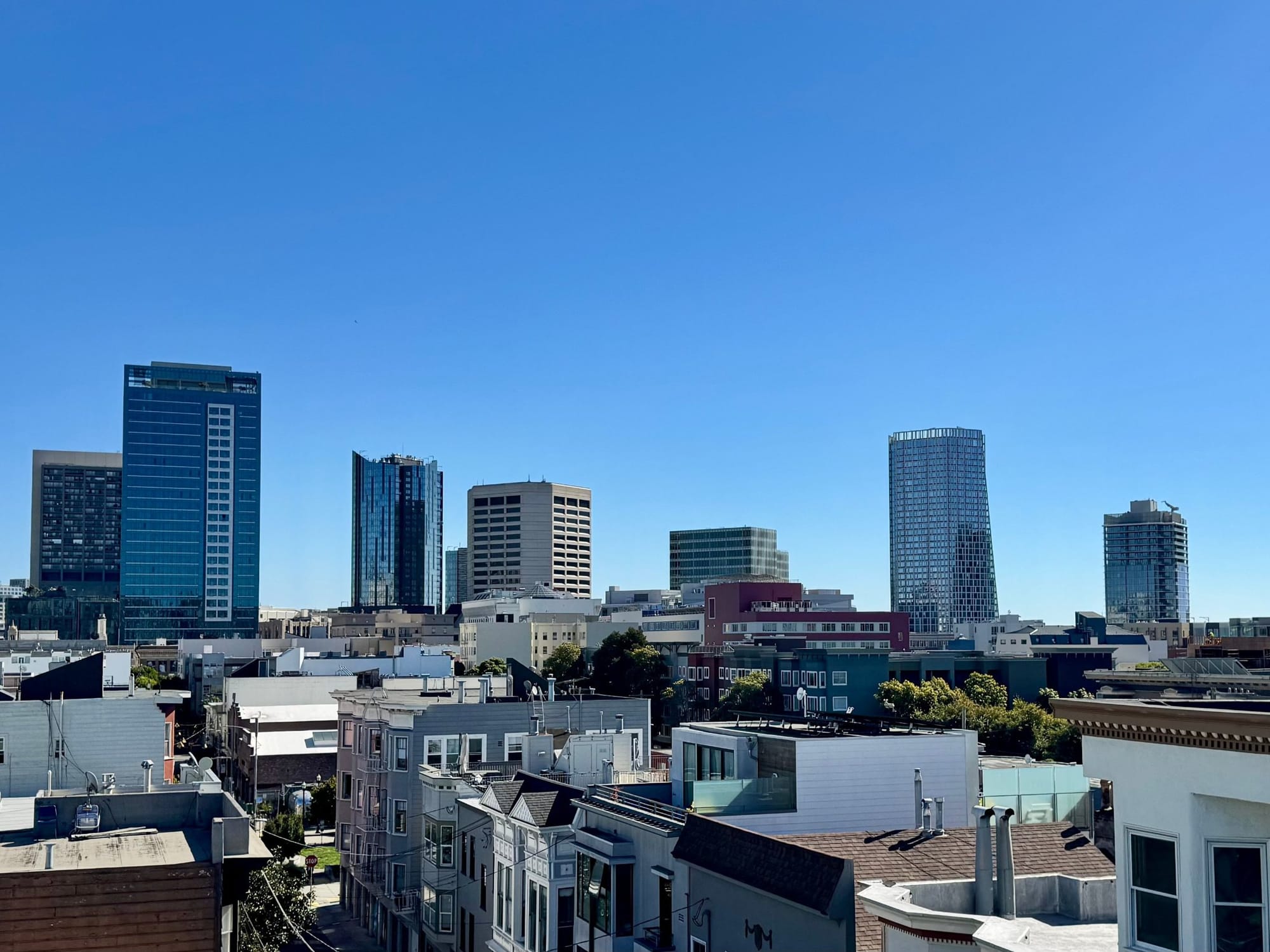 Towers around the Hub, where Market meets Van Ness, over Hayes Valley rooftops, seen from a roof deck