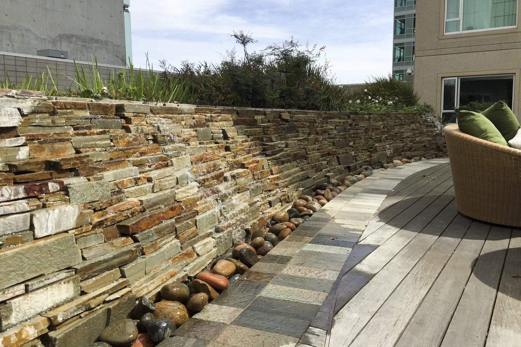 The stacked-stone planter wall and wood deck on the fifth-floor park level at SOMA Grand