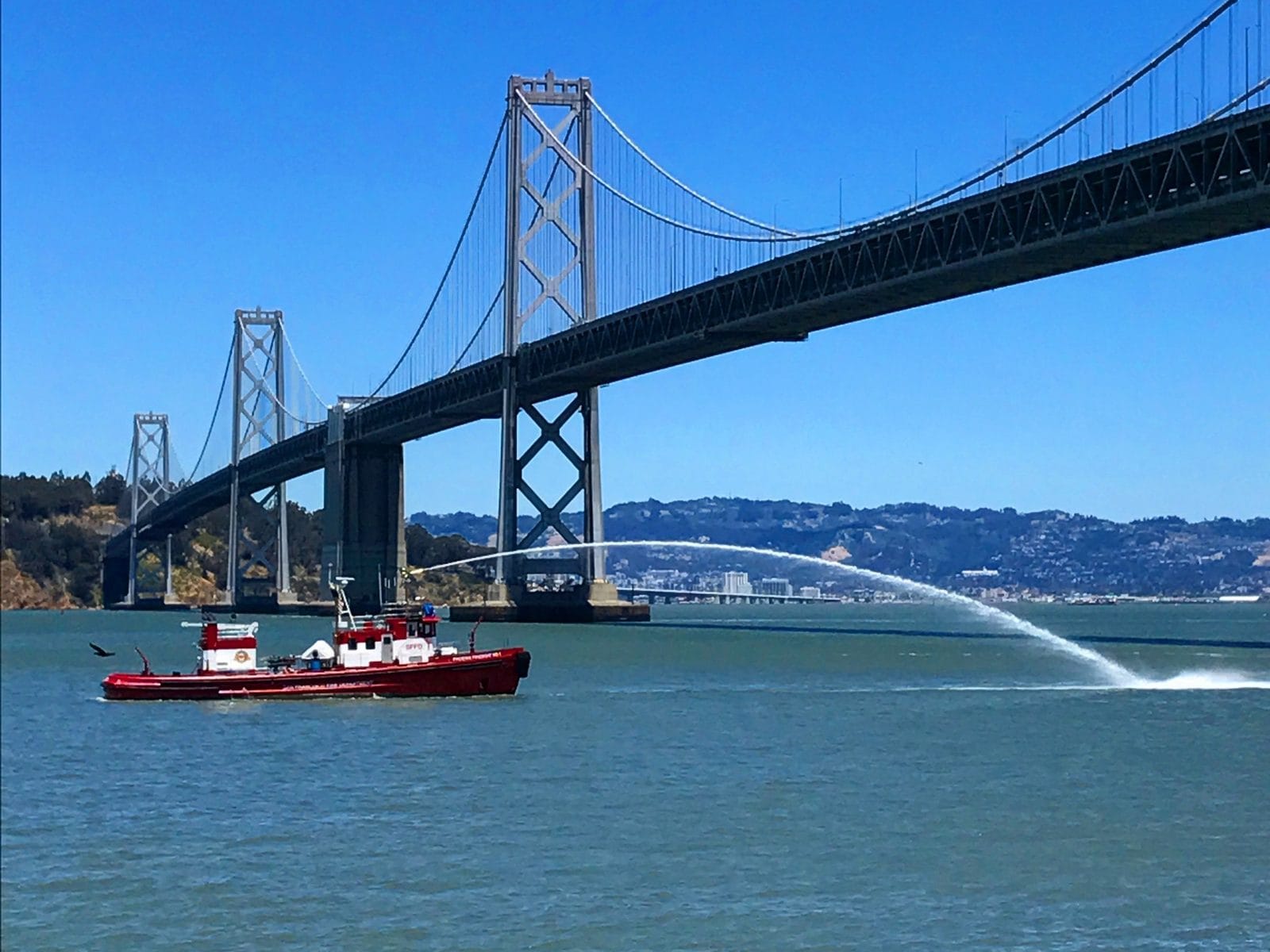 A fireboat spraying water under the Bay Bridge