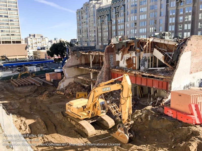 An excavator working behind the retained brick facade at 1688 Pine Street