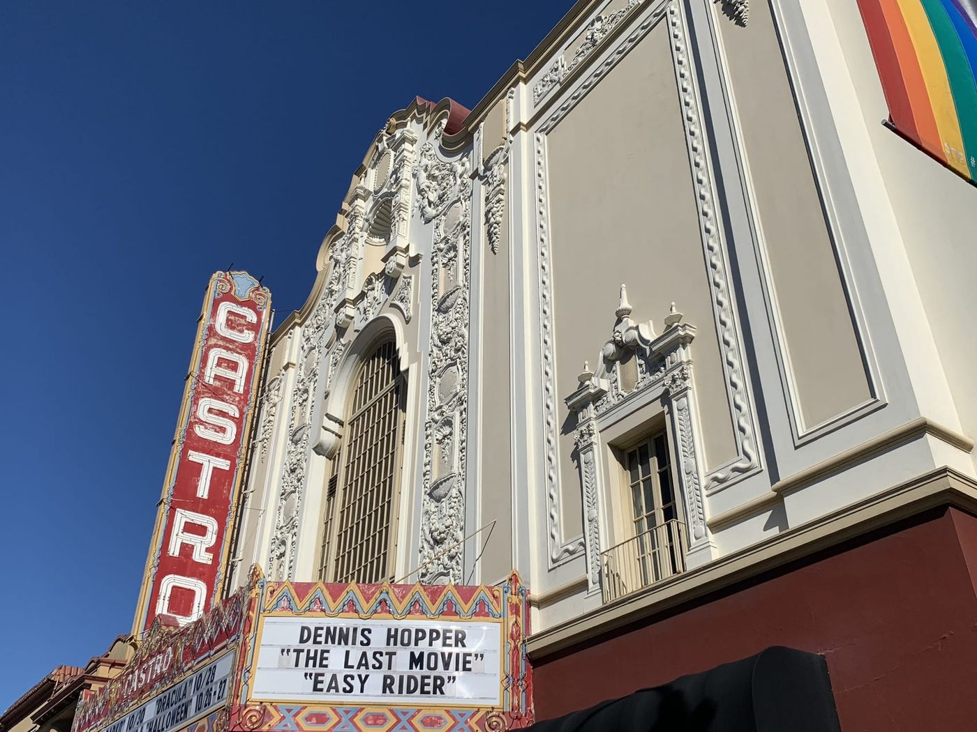 The Castro Theatre sign against a blue sky, with a rainbow flag at the corner