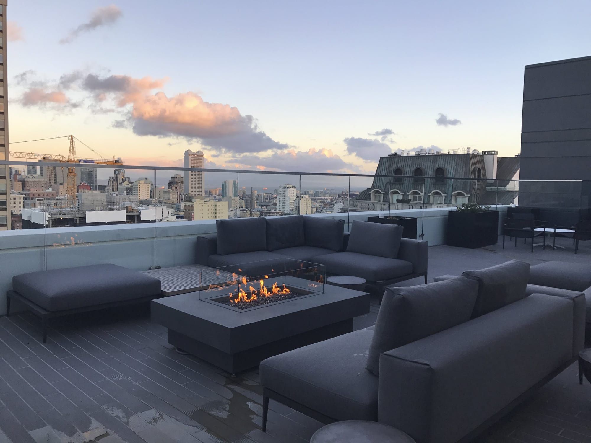 The roof deck at The Rockwell at sunset, with the downtown skyline beyond the glass rail