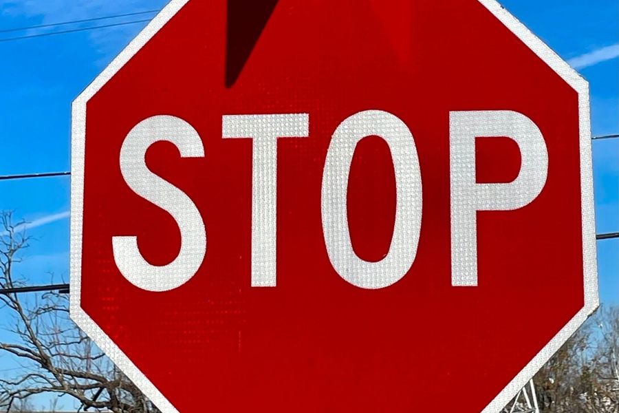 Red stop sign under a Frisco Street sign against a blue sky