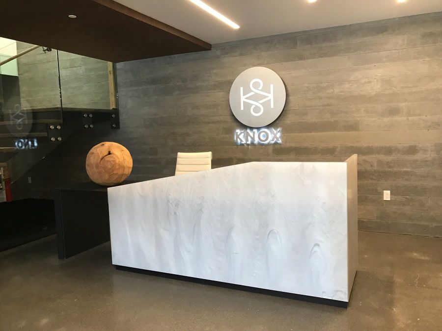The lobby at The Knox with its concrete wall, backlit KNOX sign and stone reception desk