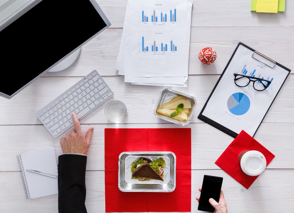 This is a an overhead photo of someone's desk, with some healthy food in front of them, but they're clearly still working at the same time