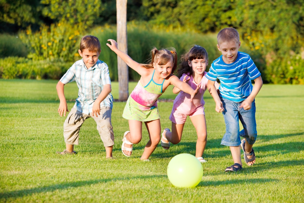 Children chase a ball in the park