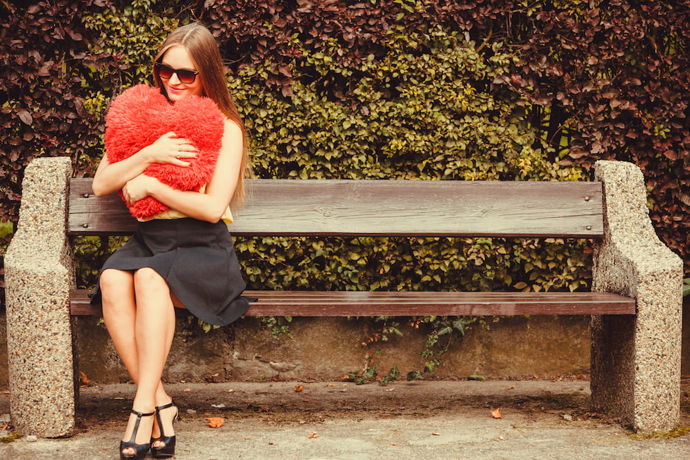 This is a photo of a woman sitting on a bench, holding a heart