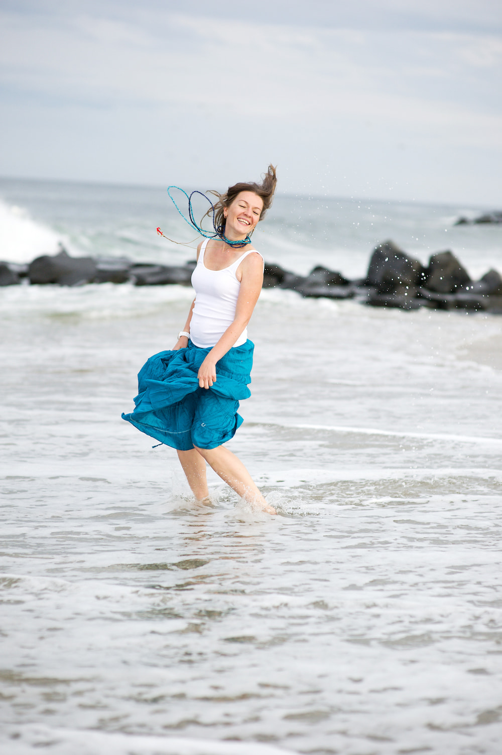 Woman wading in the sea, wearing crystals in jewellery