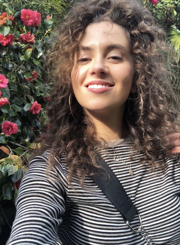 Suz smiling next to a flower bush