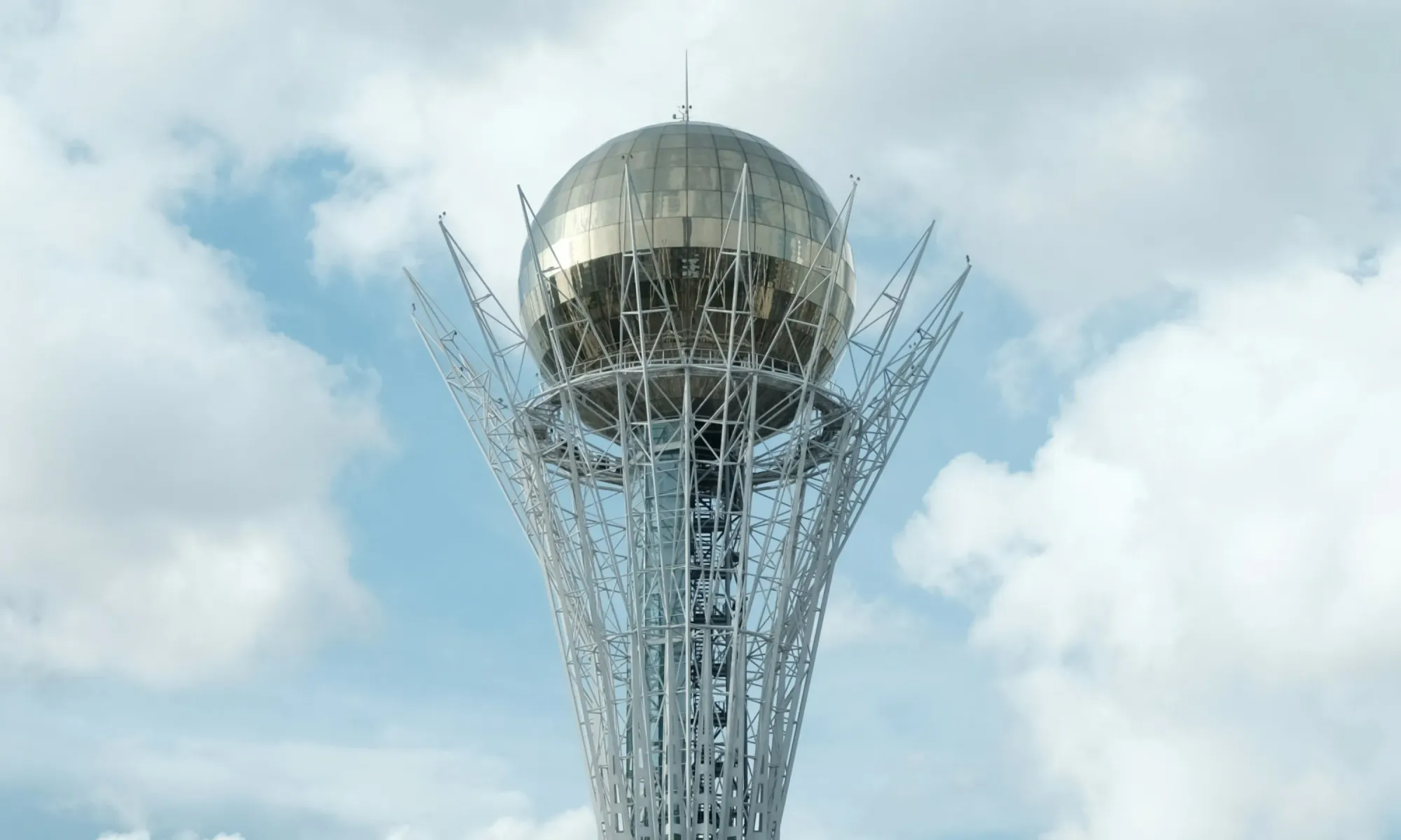 The Baiterek Tower in Astana, Kazakhstan, with a golden sphere on top against a cloudy sky.