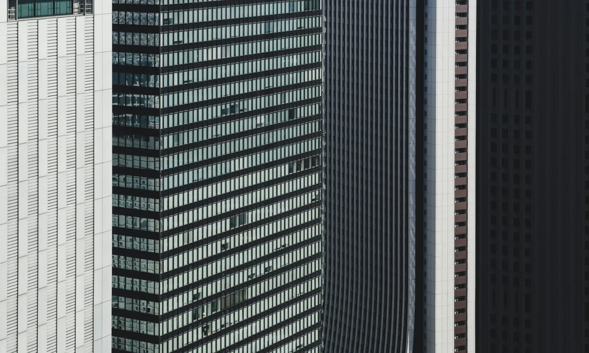 Shinjuku skyline in Tokyo – panoramic view of the business district with skyscrapers, including the Mode Gakuen Cocoon Tower, against a dense urban backdrop.