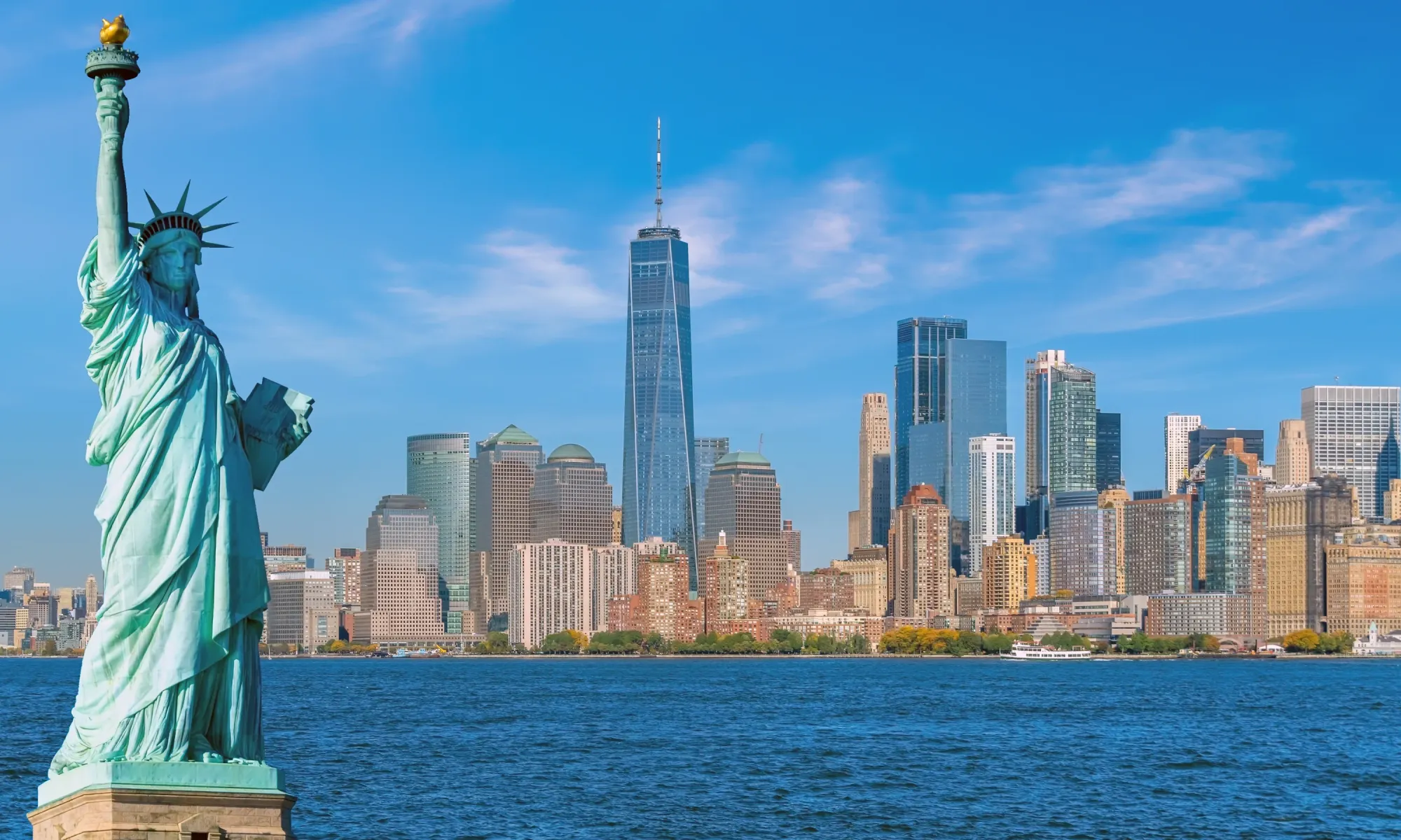 Statue of Liberty with the Manhattan skyline in the background, featuring One World Trade Center.