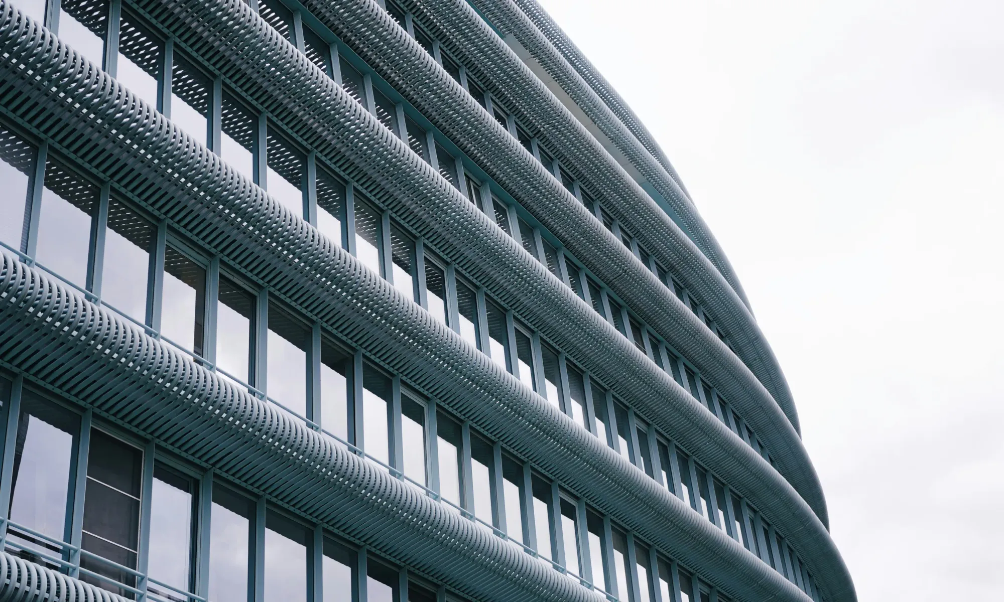 Close-up of a modern building façade with curved horizontal louvers and glass windows.