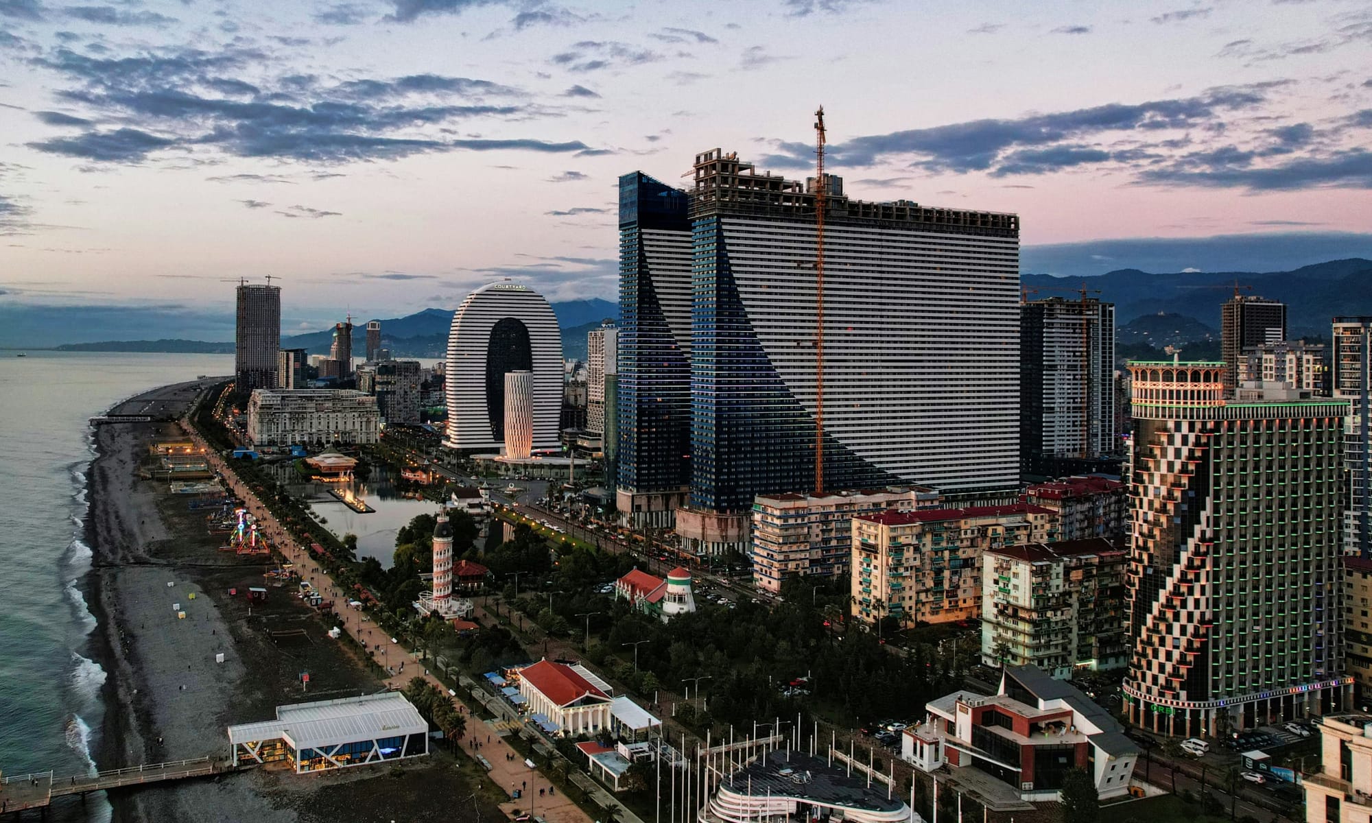 Batumi Black Sea skyline at sunset – Aerial view of Batumi’s coastline with modern skyscrapers, unique high-rise designs, and the beach stretching along the Black Sea.