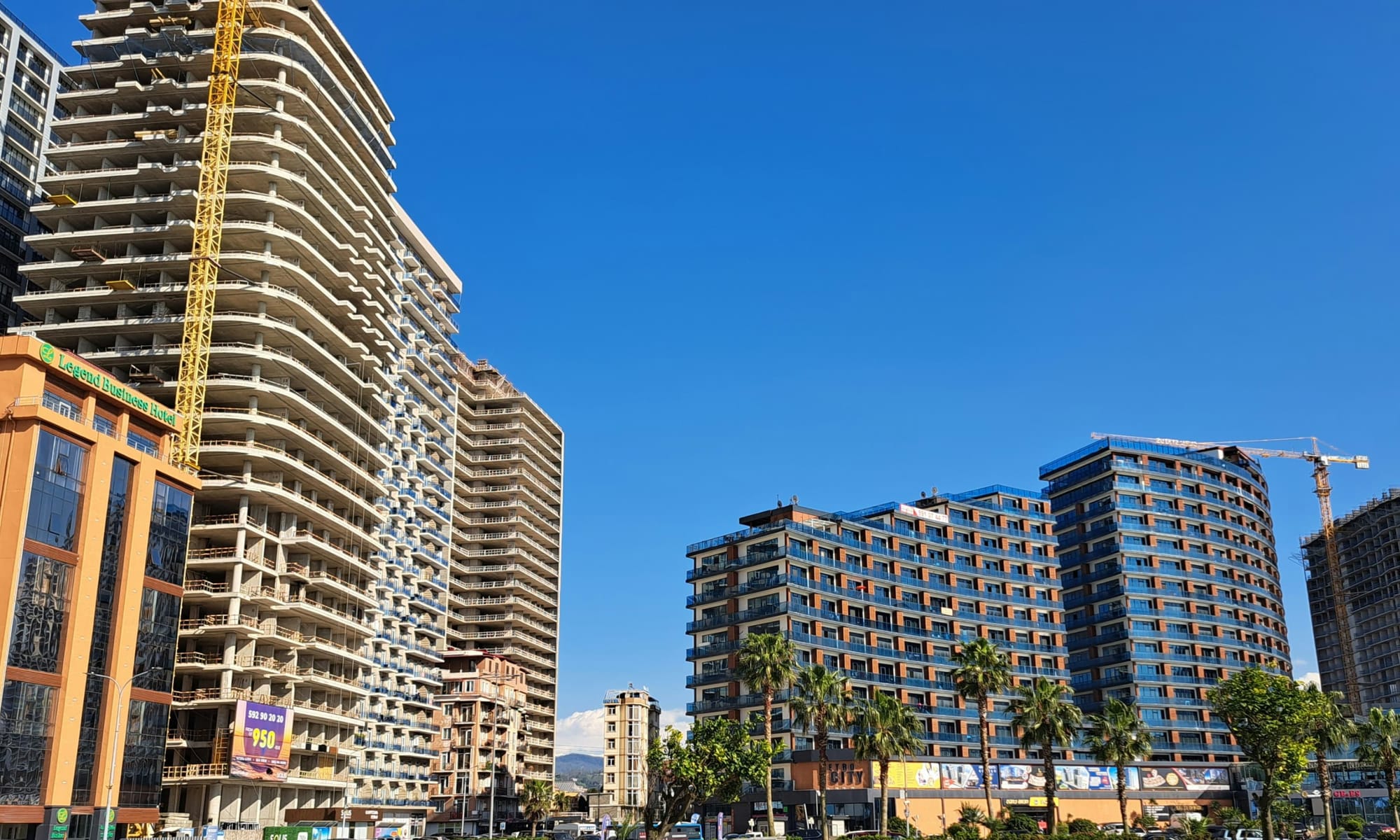 Modern apartment construction in Batumi – High-rise residential buildings under construction in Batumi, Georgia, with cranes and new developments under a clear blue sky.