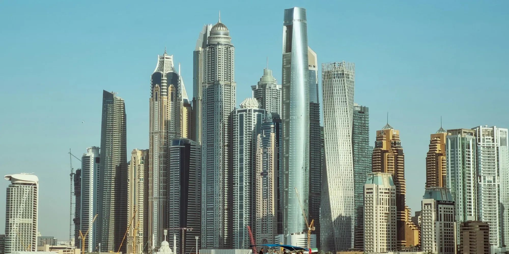 Modern skyscrapers of Dubai Marina against a clear blue sky, showcasing futuristic and diverse high-rise architecture.