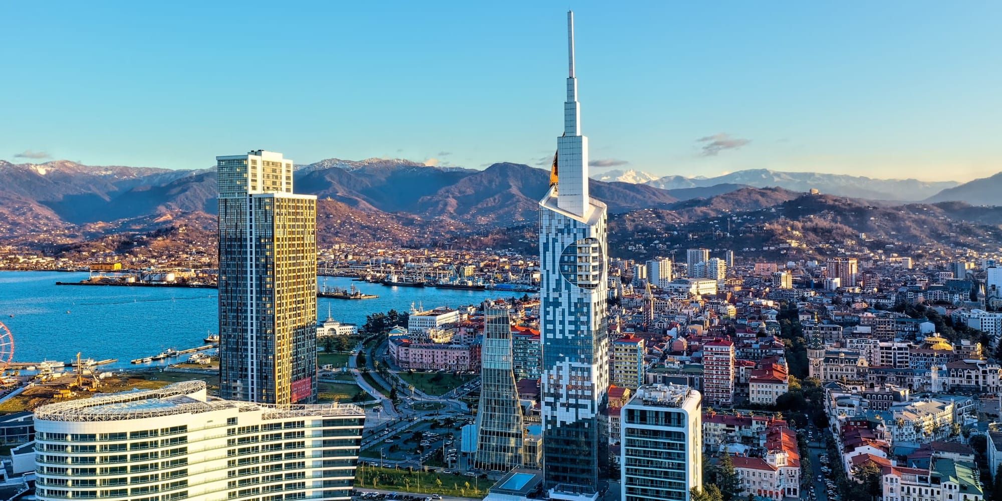 Batumi skyline and mountains – Aerial view of Batumi’s modern high-rises by the Black Sea, with mountains in the background and the iconic tower with a golden Ferris wheel feature.