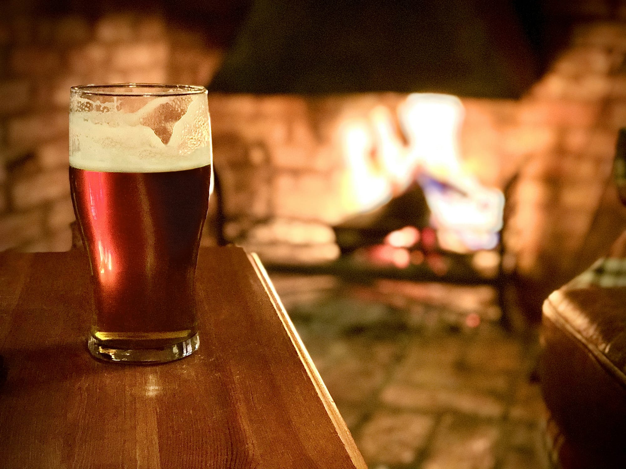 A pint of beer in front of an open fire