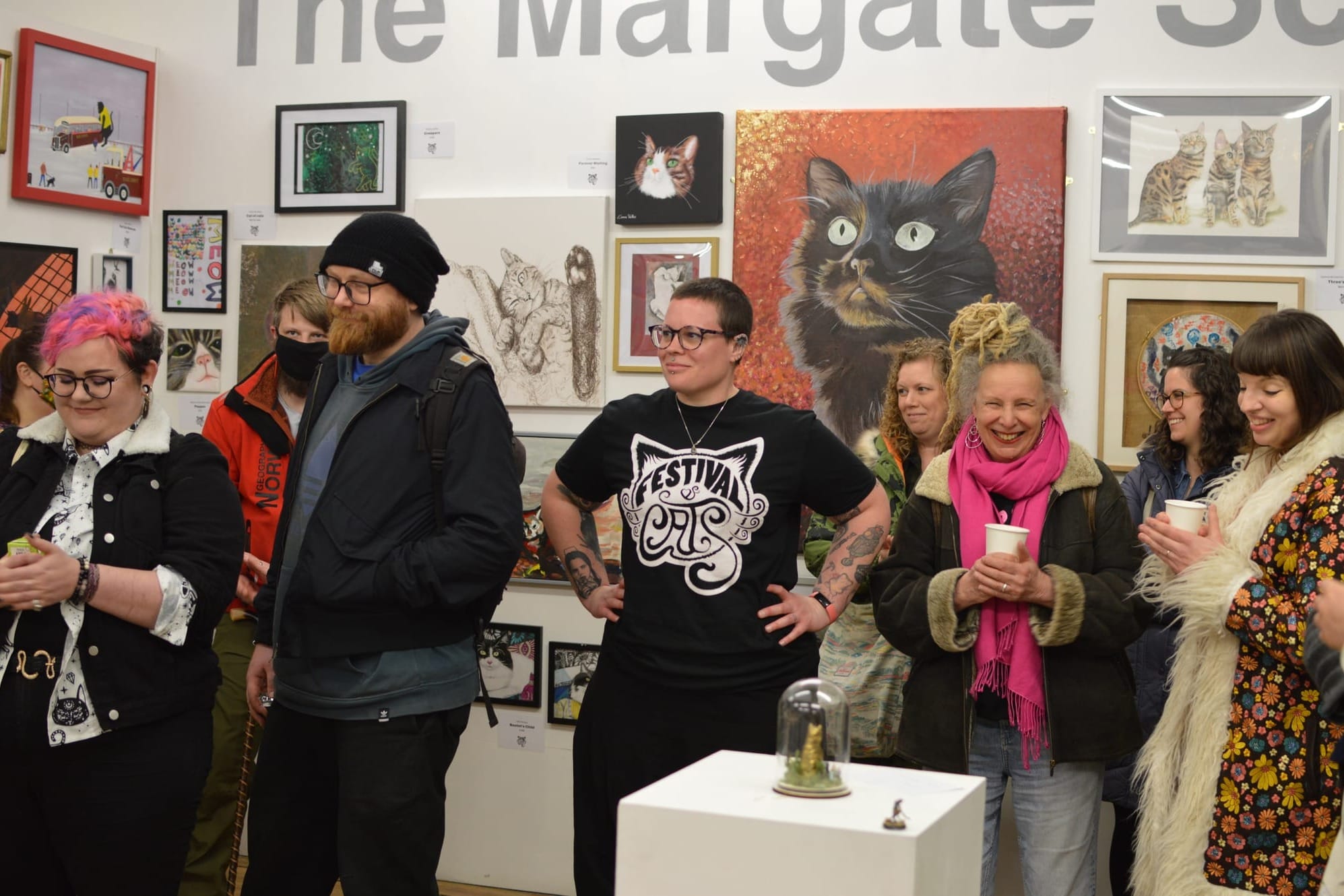 Audience listening to a speech in front of many artworks of cats