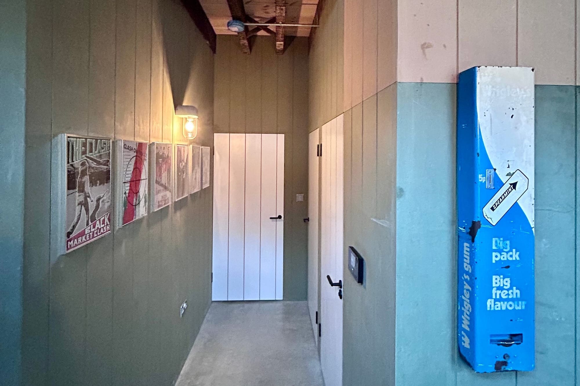 A corridor with artwork on the walls, as well as a vintage gum machine
