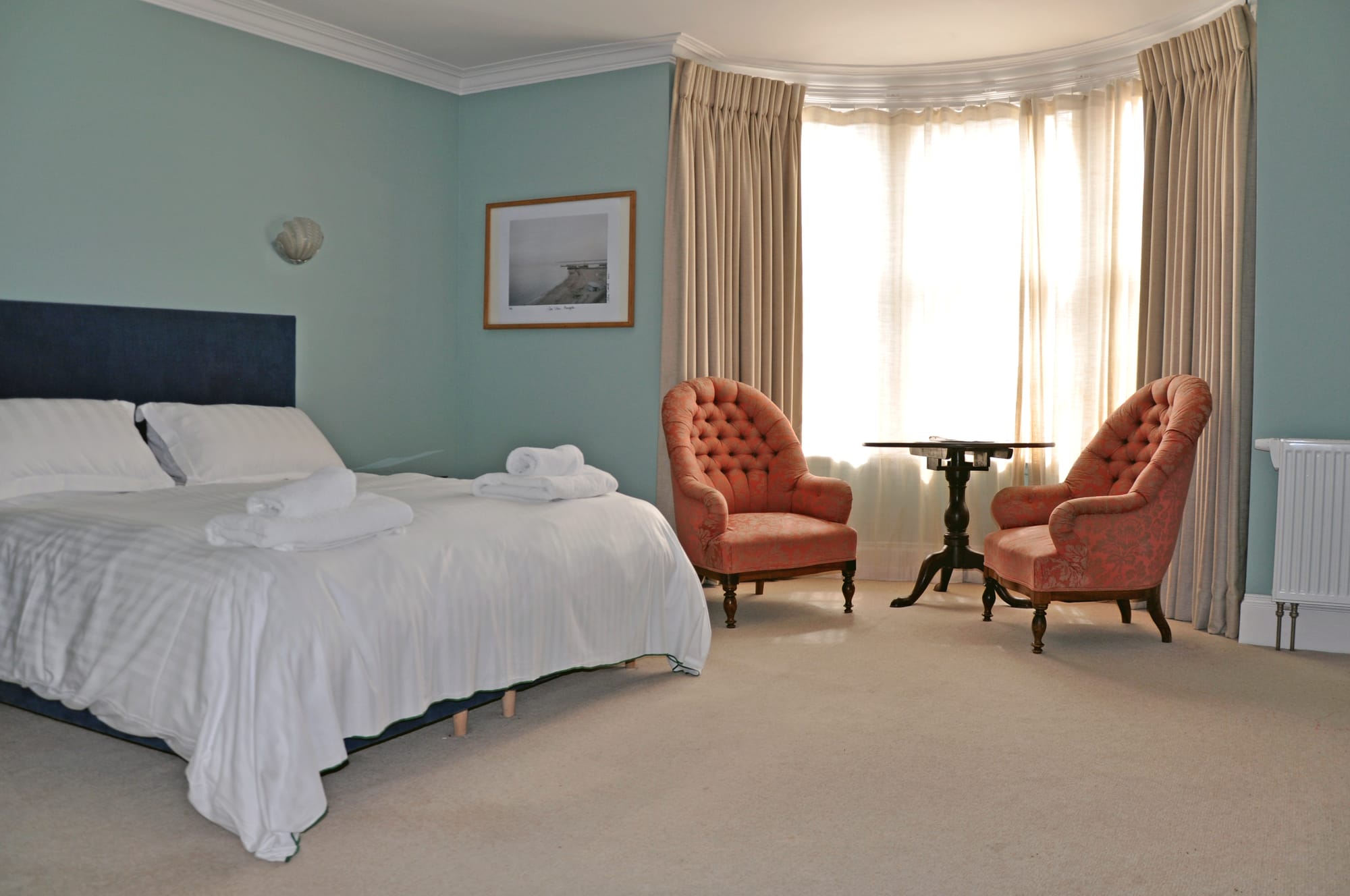 A hotel room with bed and two armchairs