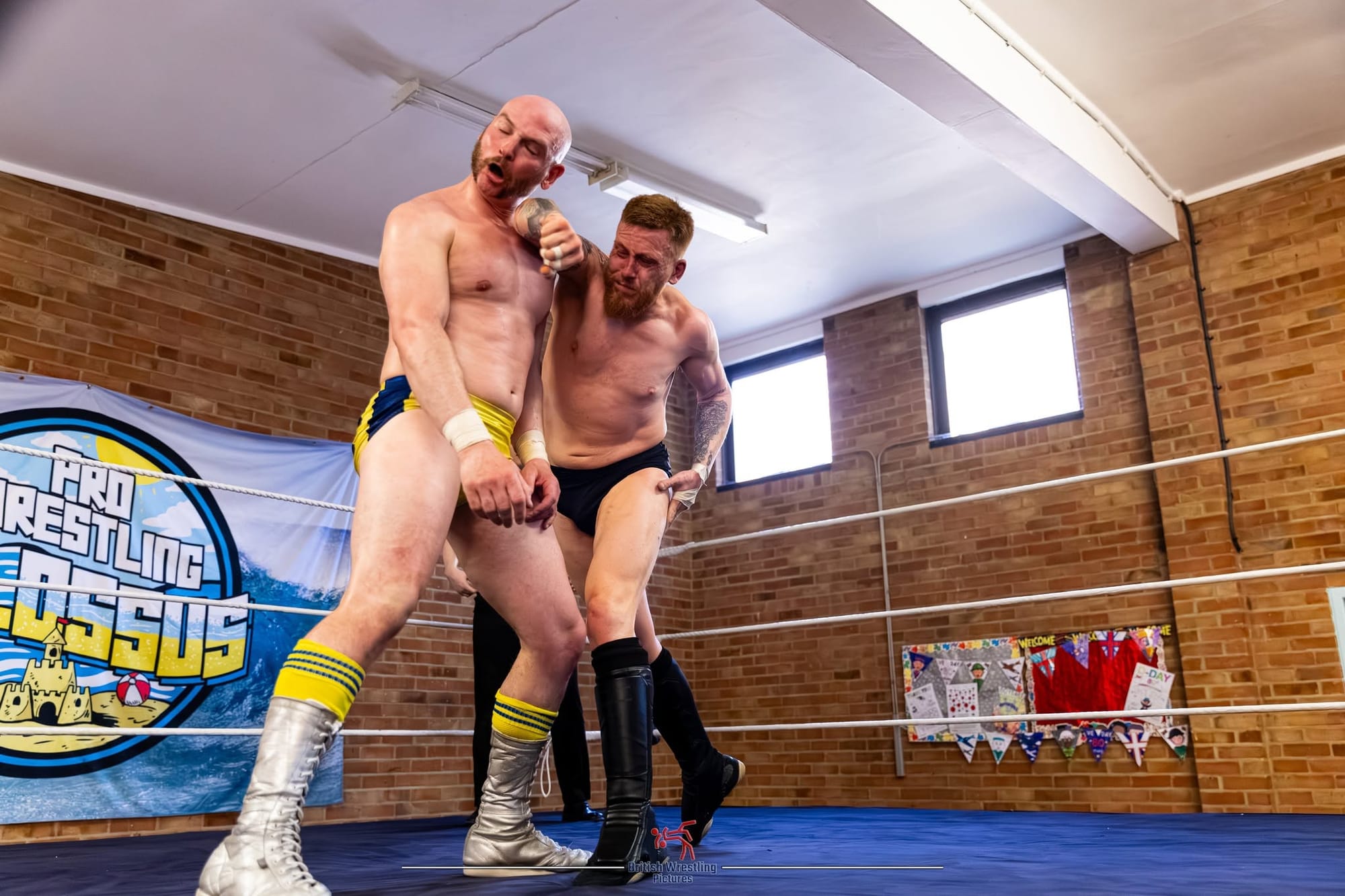 One wrestler punching another wrestler in the face while standing in the ring. 