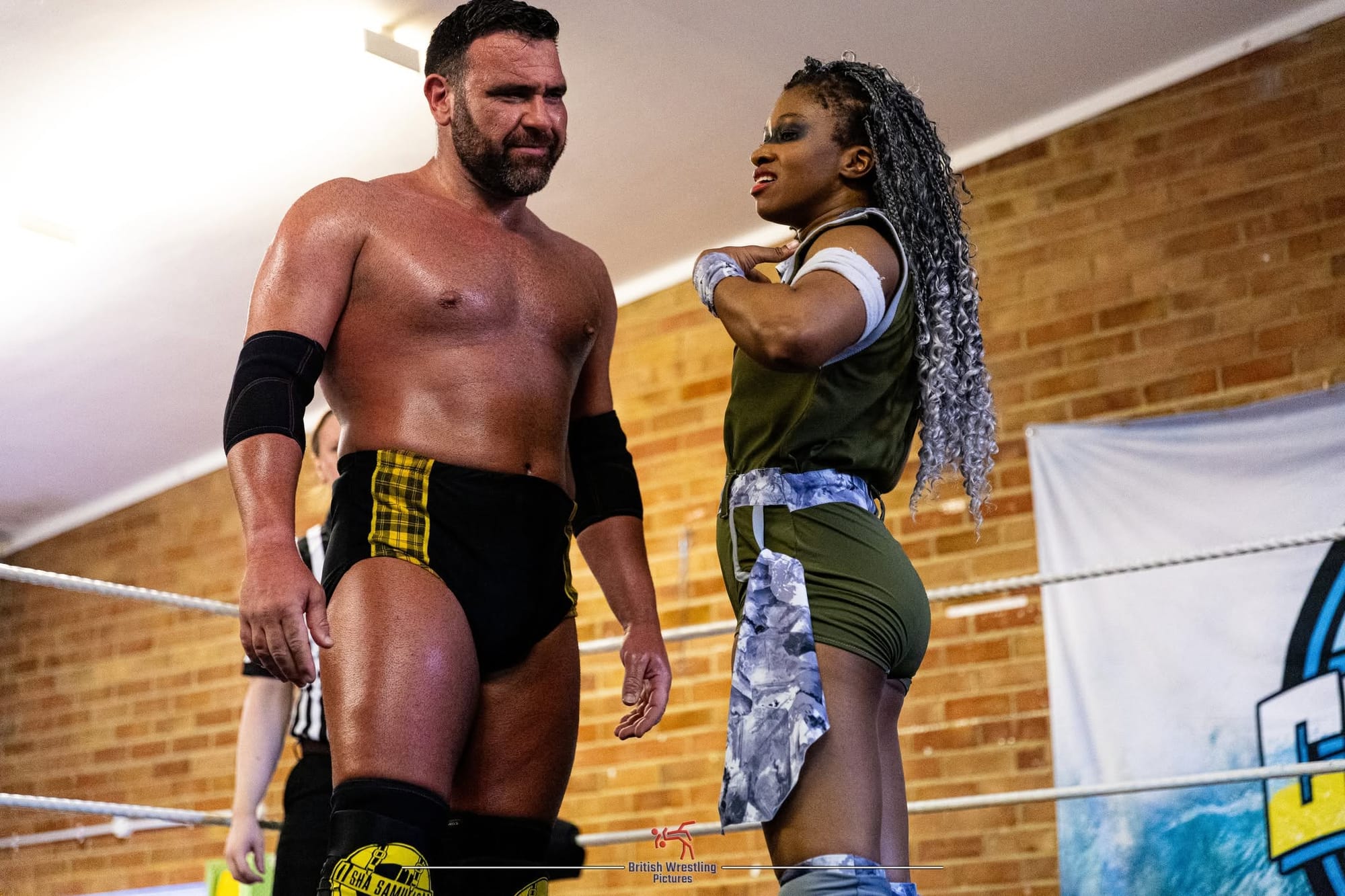 A male and female wrestler stand in the ring as if in conversation