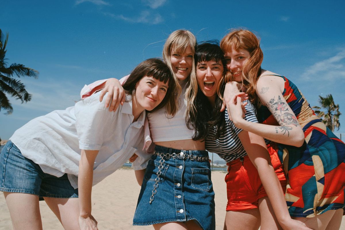 Four young women embrace on a beach