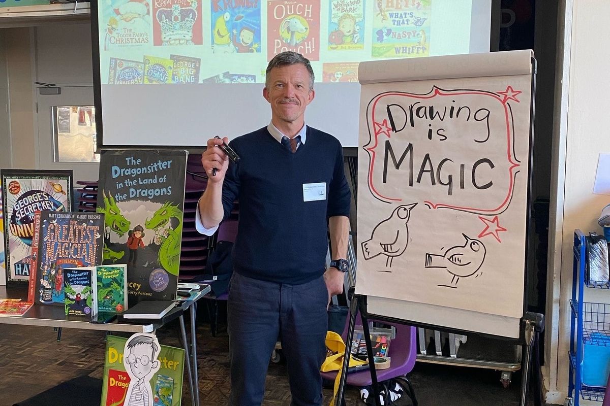 A man stands at a flipchart on which is written 'Drawing is magic' with two cartoon birds