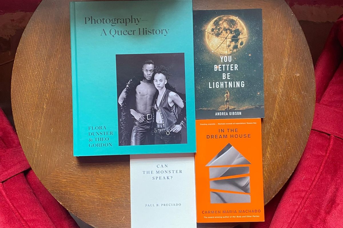 Four books sit on a round wooden table