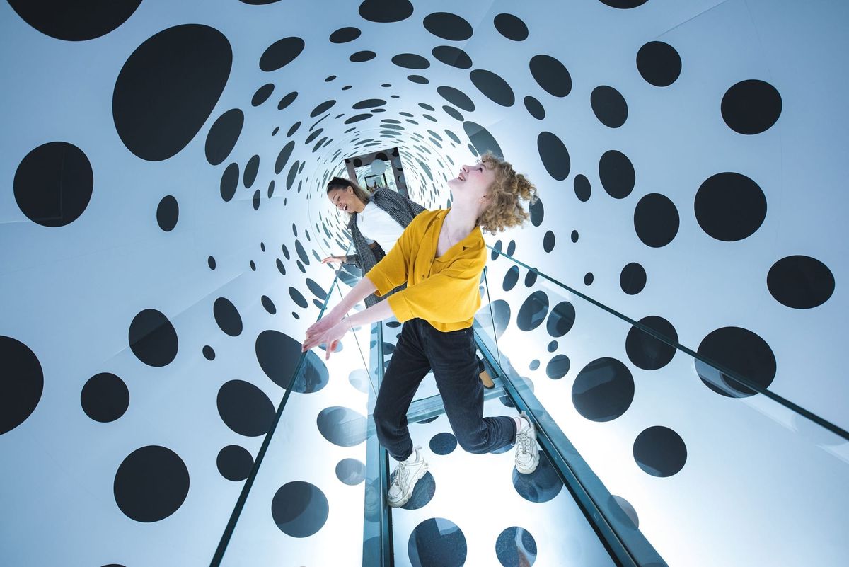 Two people inside a tunnel with white walls covered in black dots