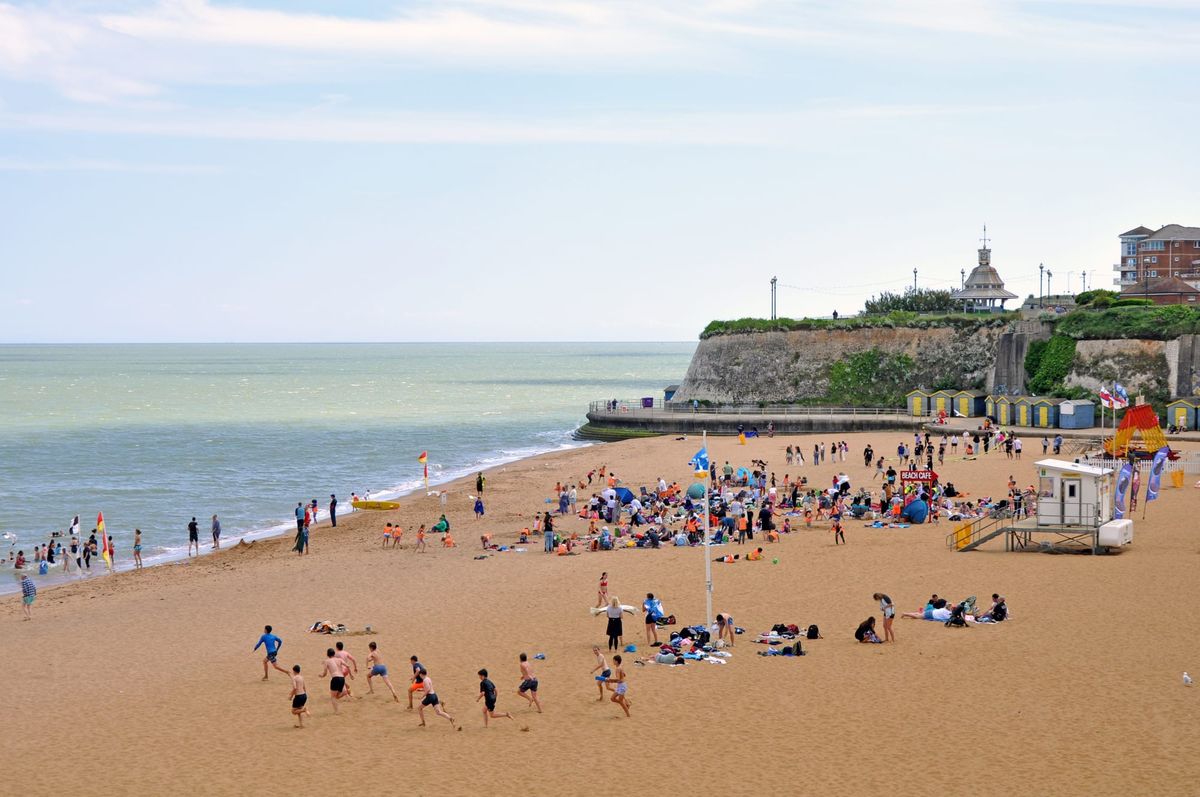 People play and relax on a beach. Some people are in the sea.