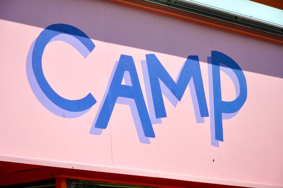 The word CAMP in blue letters on a pink background