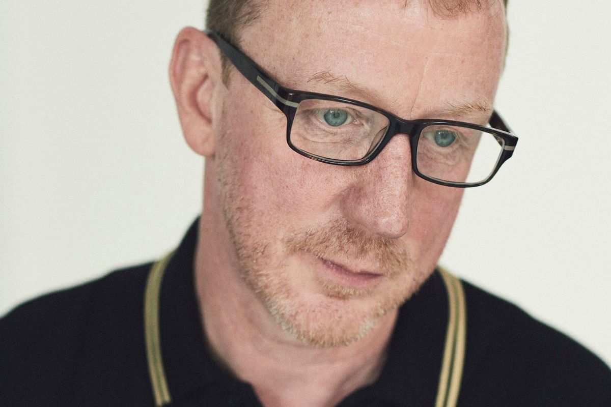 A man wearing glasses looks down out of frame