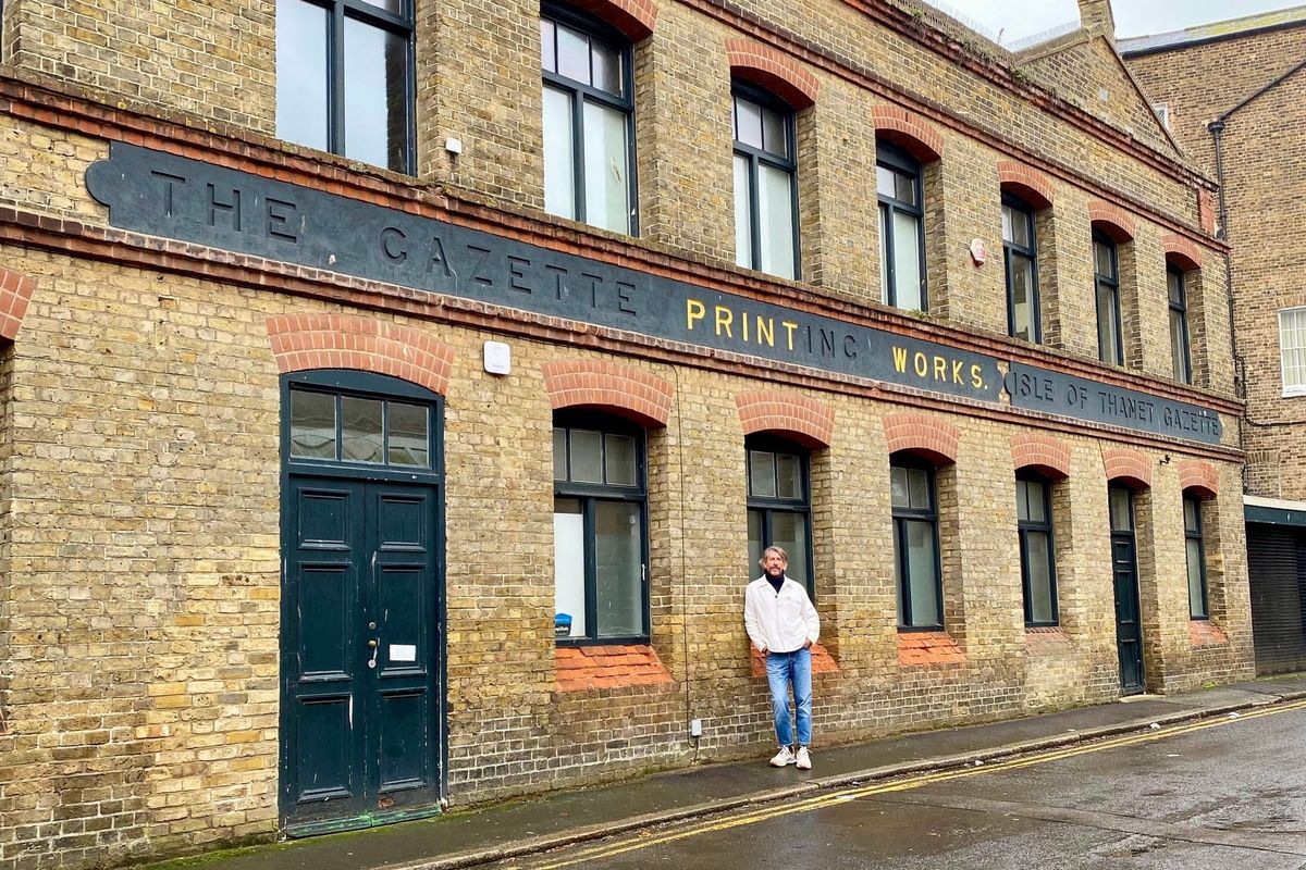 A man standing outside an industrial looking building. 