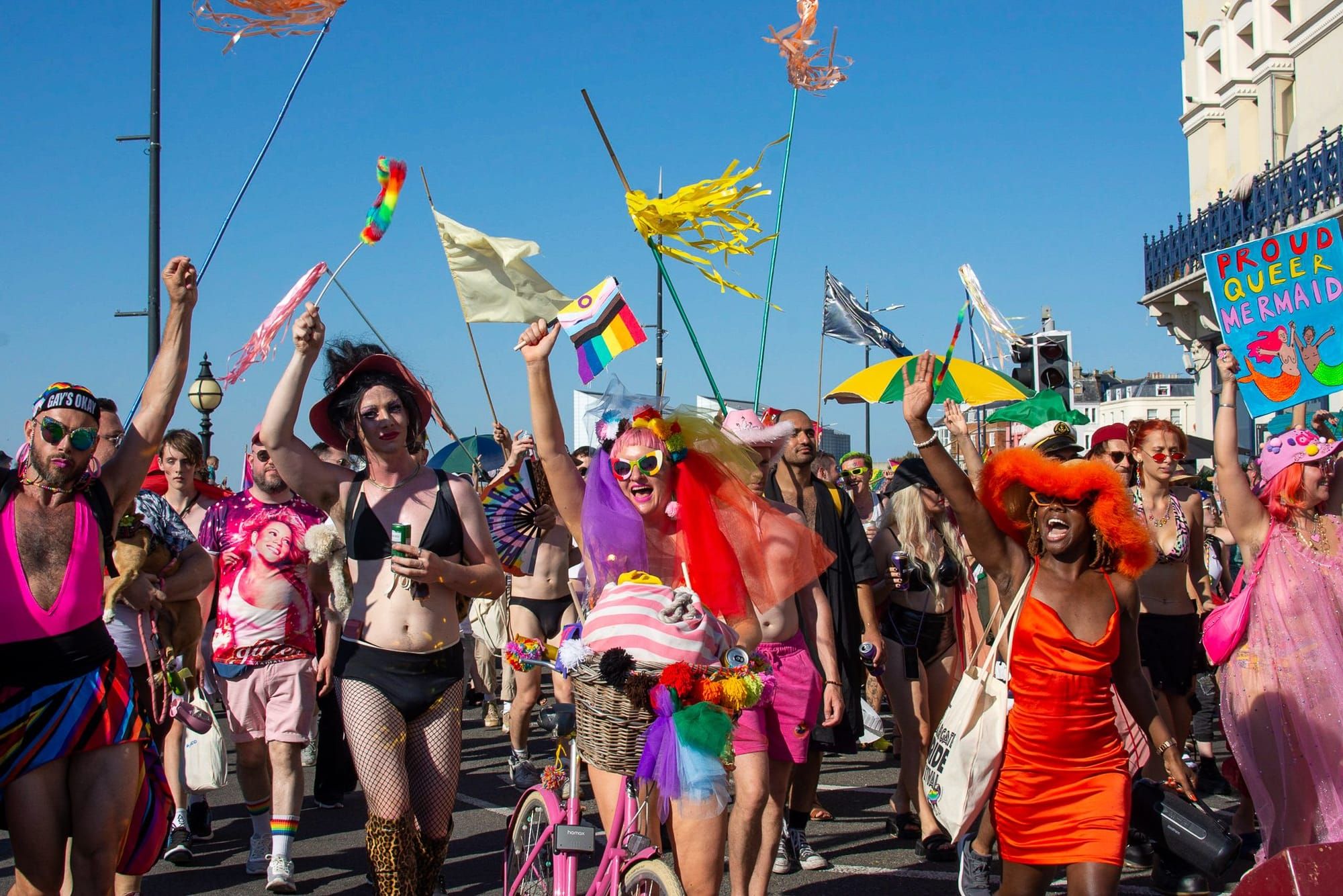 A large group of people celebrate Pride in a variety of colourful outfits.